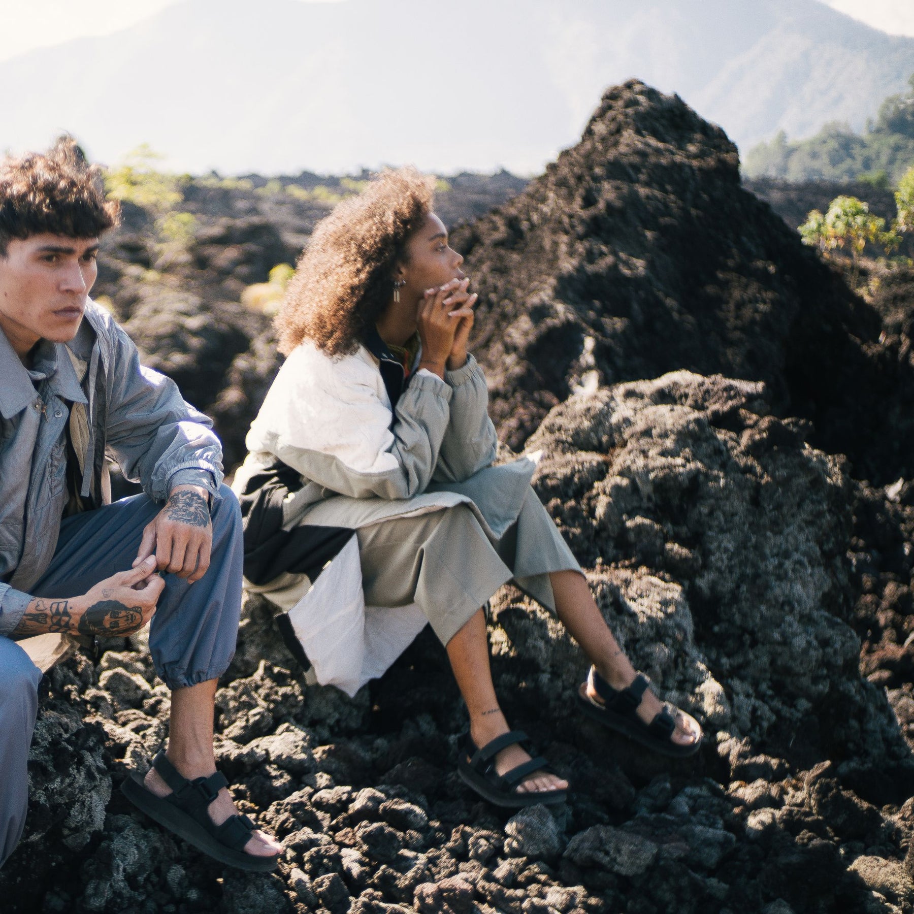 Woman and Man sitting on mountain rock wearing black adventure sandals