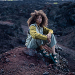 Woman sitting on volcanic rock wearing Green Adventure Sandals