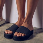 Women's feet and black platform slides