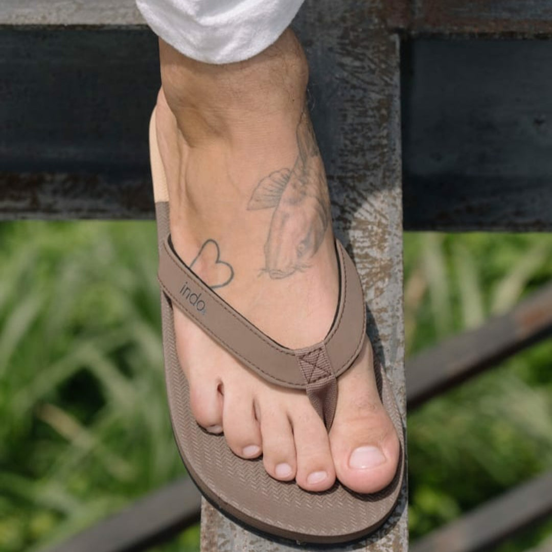 Man wearing soil flip flops and white pants
