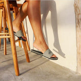 Woman wearing granite flip flops sitting on a wooden stool (2385873797197)