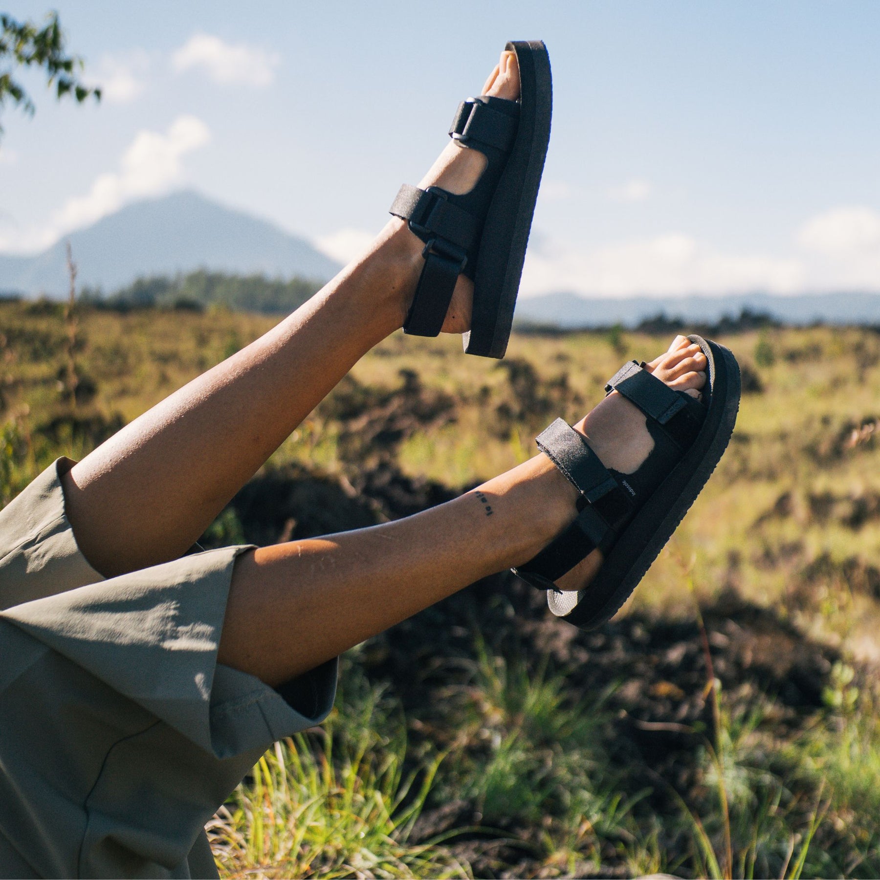 Woman's feet in Black Adventure Sandals in air