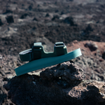 Green adventure sandal with adjustable straps leaning on a rock on mountainside