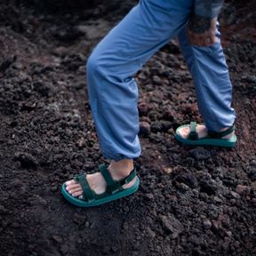 Man walking on gravel on mountainside wearing rugged sandals