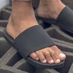 Man wearing black slides standing on cement bricks