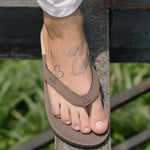 Man wearing soil flip flops and white pants