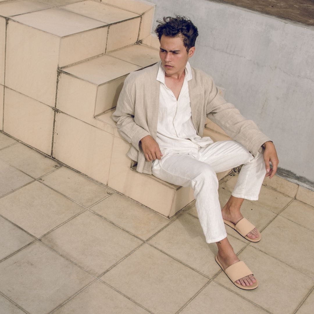 Man wearing light soil slides sitting on stairs