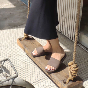 Woman wearing soil slides standing on a wooden swing