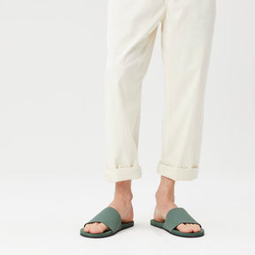 Man wearing green beach slides with white trousers