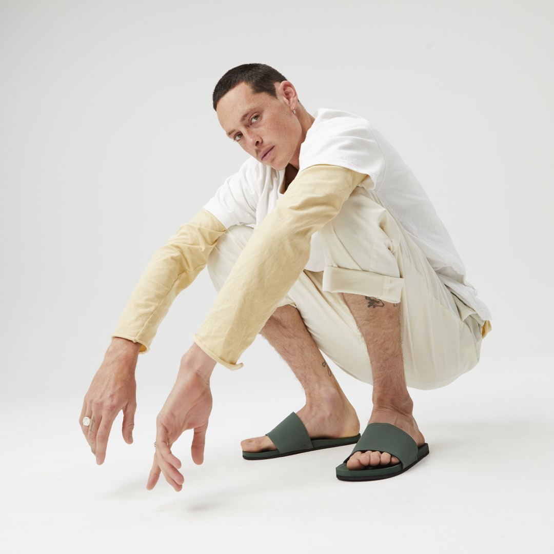 Man wearing green leaf slides with white trousers