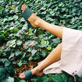 Woman wearing leaf slides whilst lying on grass