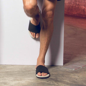 A man wearing slides color sea salt/black