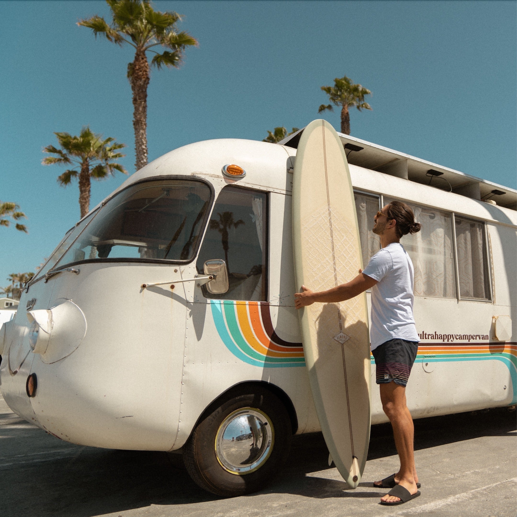 Man with surfboard wearing men's slides in black