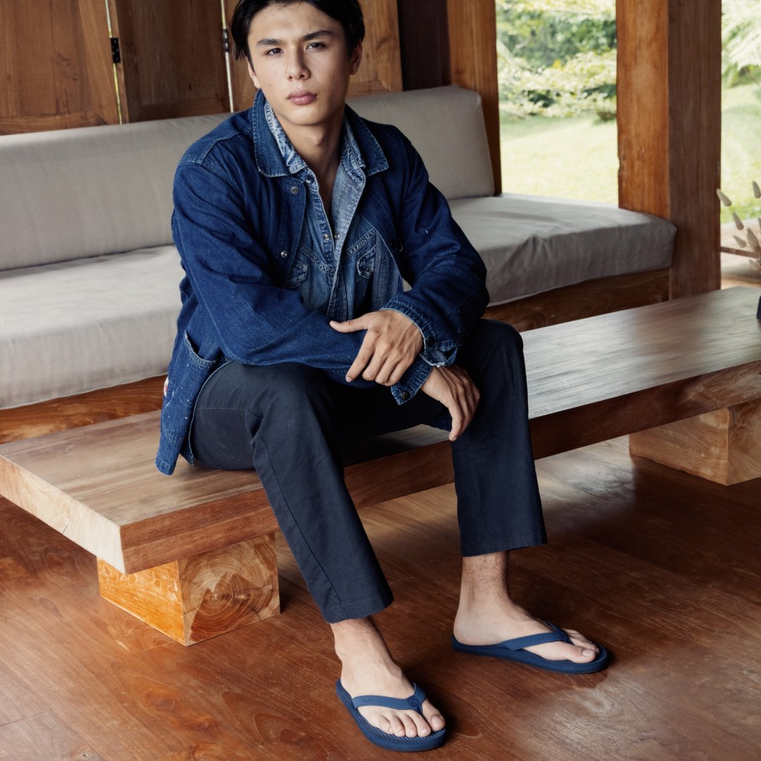 A man wearing jacket and shore flip flops